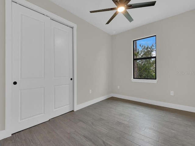 unfurnished bedroom with a ceiling fan, baseboards, and wood finished floors