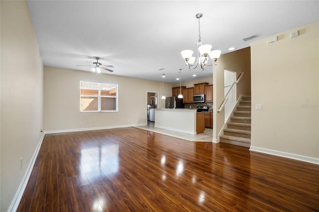 unfurnished living room featuring ceiling fan with notable chandelier and dark hardwood / wood-style flooring