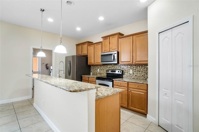 kitchen with appliances with stainless steel finishes, hanging light fixtures, tasteful backsplash, an island with sink, and light tile patterned flooring