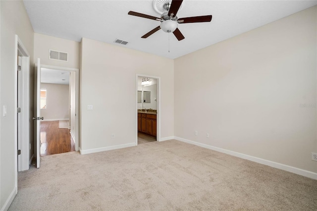 unfurnished bedroom with ceiling fan, light colored carpet, and ensuite bathroom