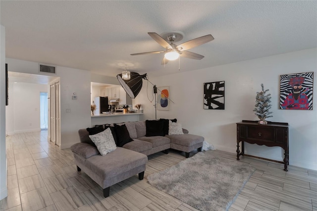 living room featuring ceiling fan and a textured ceiling