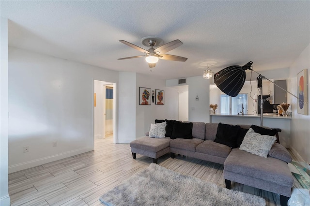 living room featuring ceiling fan and a textured ceiling