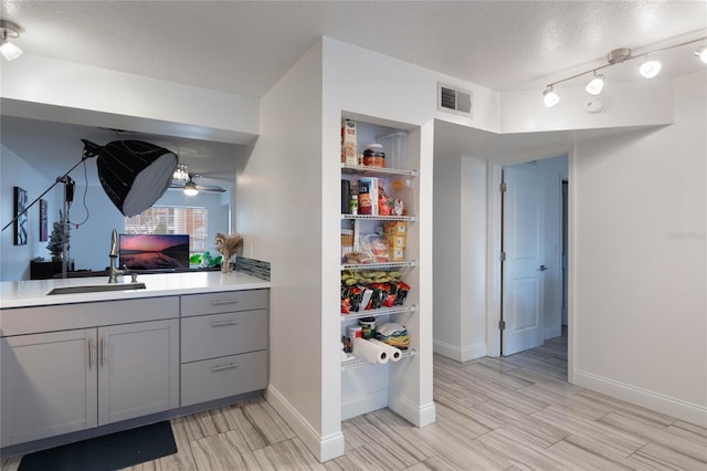 interior space featuring gray cabinetry, ceiling fan, sink, and a textured ceiling