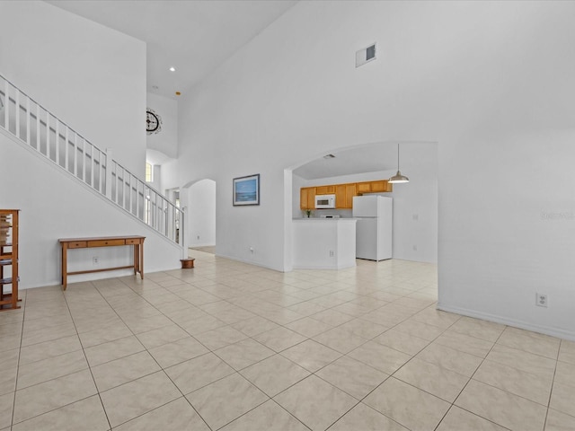 unfurnished living room with a high ceiling and light tile patterned floors