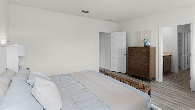 bedroom with hardwood / wood-style flooring and connected bathroom