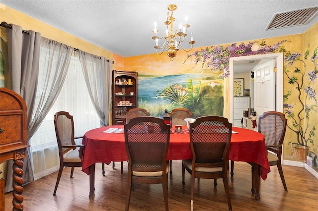 dining room with a textured ceiling, hardwood / wood-style flooring, and a notable chandelier