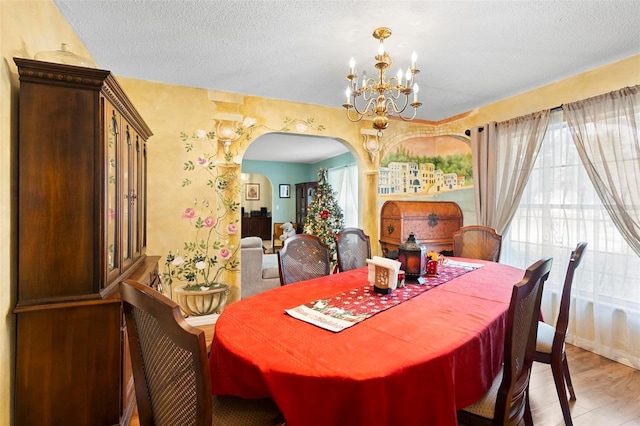 dining space featuring a textured ceiling, hardwood / wood-style flooring, and an inviting chandelier