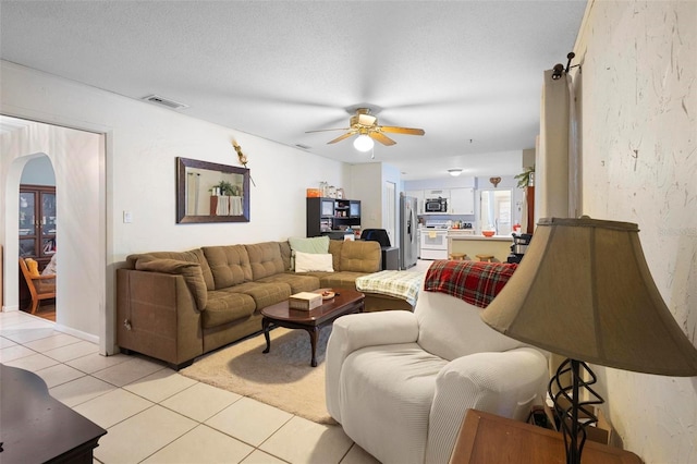 tiled living room featuring ceiling fan and a textured ceiling