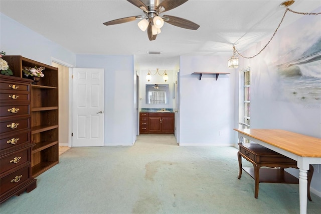 interior space featuring connected bathroom, light colored carpet, and ceiling fan with notable chandelier