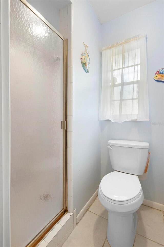 bathroom with tile patterned floors, a shower with shower door, and toilet