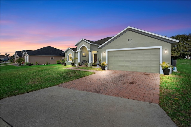 ranch-style home with central air condition unit, a garage, and a lawn