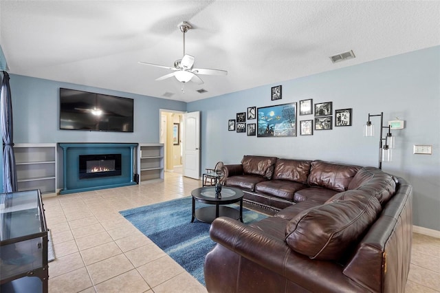 living room with ceiling fan, light tile patterned floors, and a textured ceiling