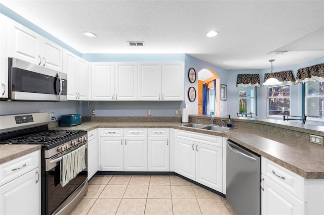 kitchen with sink, hanging light fixtures, stainless steel appliances, kitchen peninsula, and white cabinets