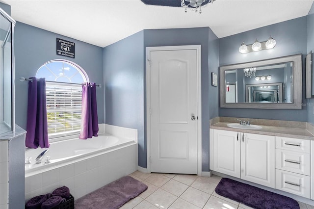 bathroom with tile patterned flooring, vanity, and tiled bath