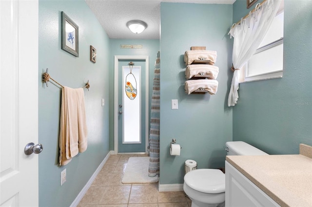 bathroom with tile patterned flooring, vanity, toilet, and a textured ceiling