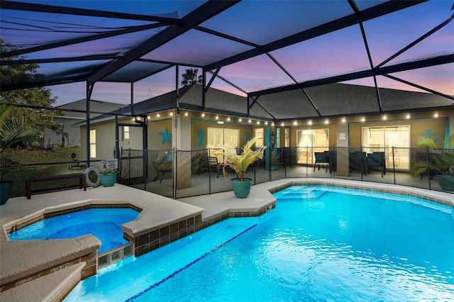 pool at dusk with a patio area, a lanai, and an in ground hot tub