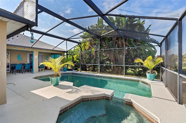 view of pool with a patio area, an in ground hot tub, and glass enclosure