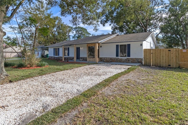 5355 Fay Blvd, Cocoa, FL 32927 - single story home with a gate, stone siding, fence, gravel driveway, and a front yard