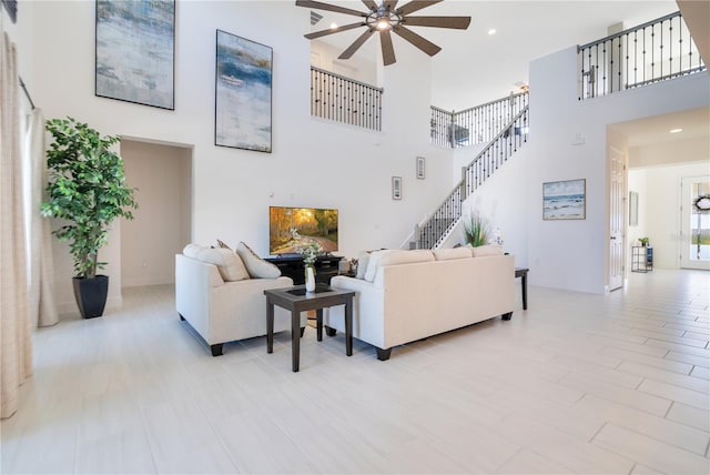 living room featuring recessed lighting, ceiling fan, a high ceiling, and stairs