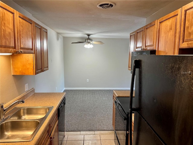 kitchen with light carpet, black appliances, sink, ceiling fan, and a textured ceiling