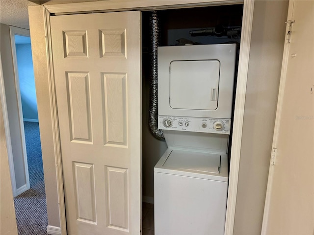 clothes washing area featuring carpet flooring, stacked washer / dryer, and a textured ceiling