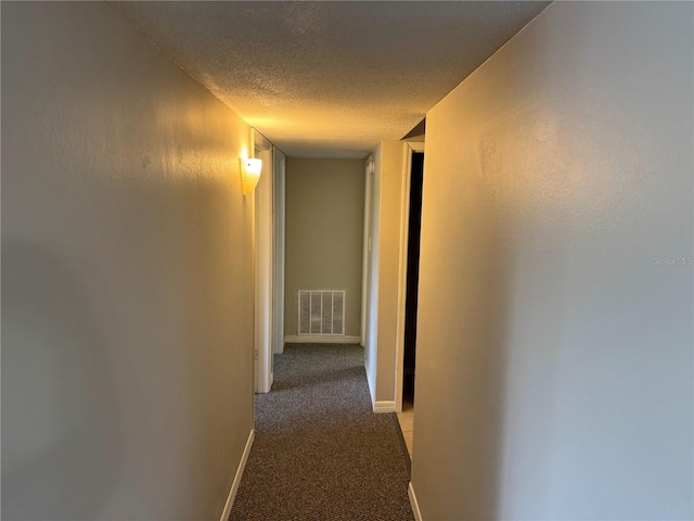 hallway with carpet floors and a textured ceiling