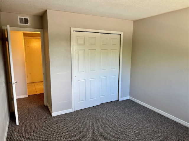 unfurnished bedroom with a closet and dark colored carpet