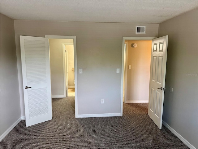 unfurnished bedroom featuring dark colored carpet and a textured ceiling