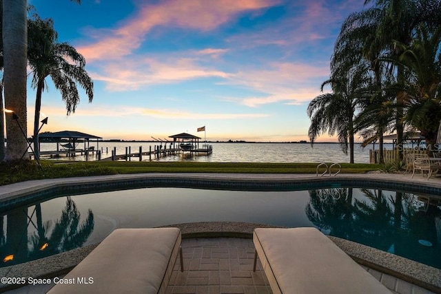 pool at dusk with a dock and a water view