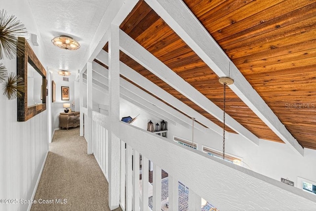 hallway with beamed ceiling, built in shelves, wooden ceiling, and light carpet