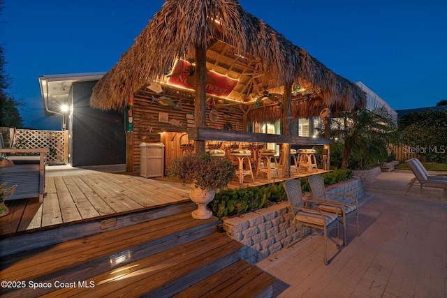 back house at twilight featuring an outdoor bar and a wooden deck