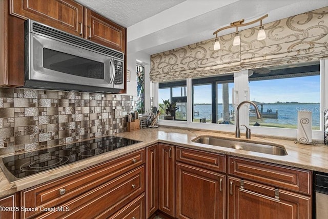 kitchen featuring black electric stovetop, a water view, a wealth of natural light, and sink