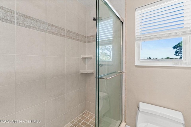 bathroom featuring an enclosed shower, toilet, and a wealth of natural light