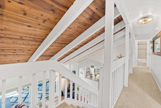 corridor with light carpet, beam ceiling, and wood ceiling