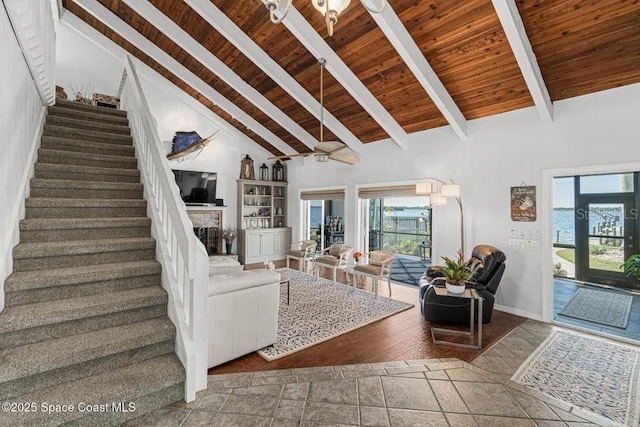 unfurnished living room featuring a stone fireplace, beamed ceiling, high vaulted ceiling, and wood ceiling