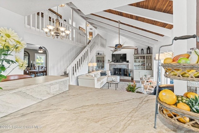 living room featuring beamed ceiling, ceiling fan with notable chandelier, wood ceiling, and high vaulted ceiling