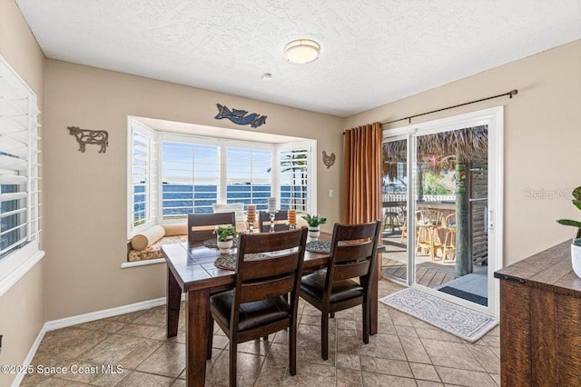 dining space featuring a water view and a textured ceiling