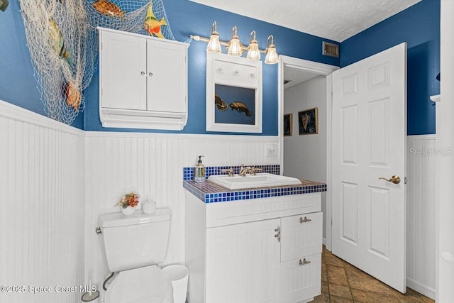 bathroom with tile patterned flooring, vanity, toilet, and a textured ceiling