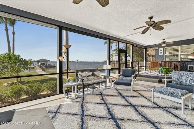 sunroom / solarium with ceiling fan and a water view