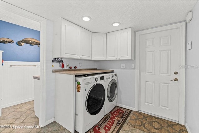 laundry area with cabinets, washer and dryer, and a textured ceiling