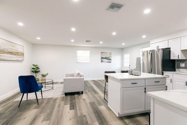 kitchen featuring stainless steel refrigerator, white cabinetry, a kitchen island, and light hardwood / wood-style floors