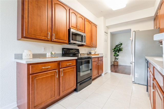 kitchen featuring ventilation hood, light tile patterned flooring, and appliances with stainless steel finishes