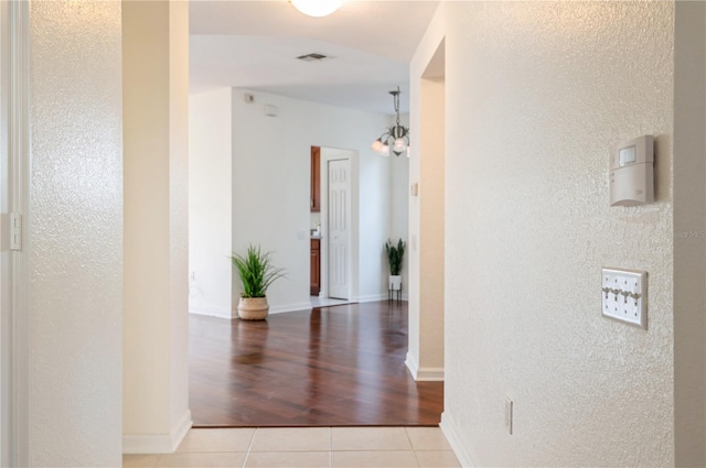 hallway featuring light tile patterned floors and a notable chandelier