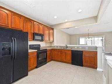 kitchen with kitchen peninsula, pendant lighting, sink, and black appliances