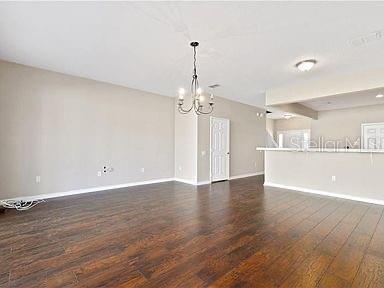 unfurnished living room featuring dark hardwood / wood-style floors and a notable chandelier