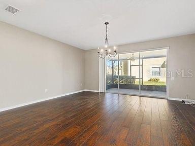 spare room with dark hardwood / wood-style floors and an inviting chandelier