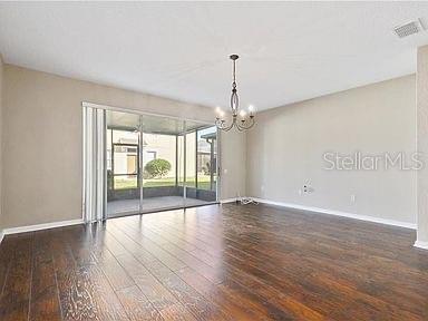 spare room with dark hardwood / wood-style flooring and an inviting chandelier