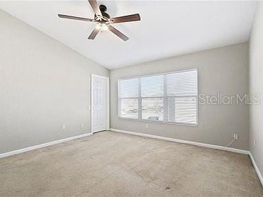 carpeted spare room with ceiling fan and lofted ceiling