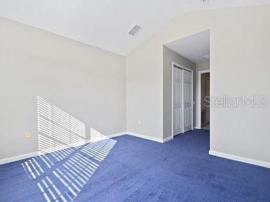 unfurnished bedroom with dark colored carpet, a closet, and vaulted ceiling