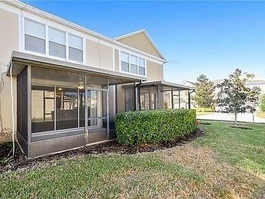 back of property featuring a lawn and a sunroom